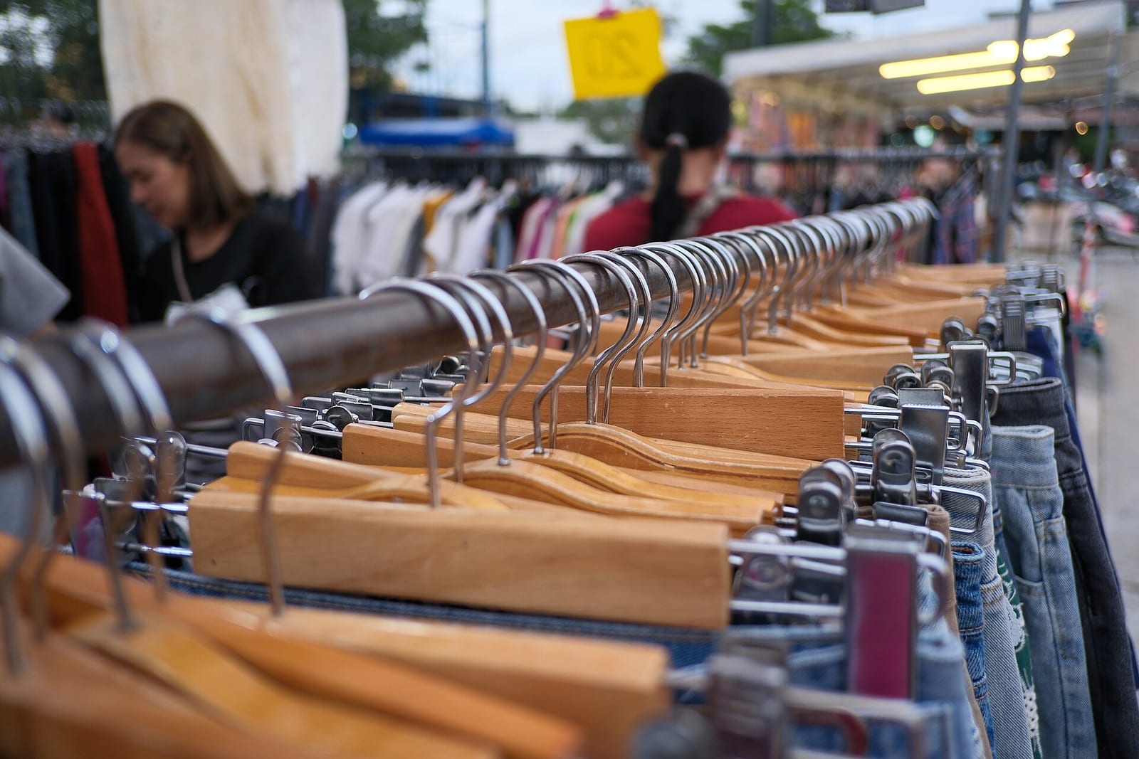 Wooden hangers on a thrift-store clothing rack